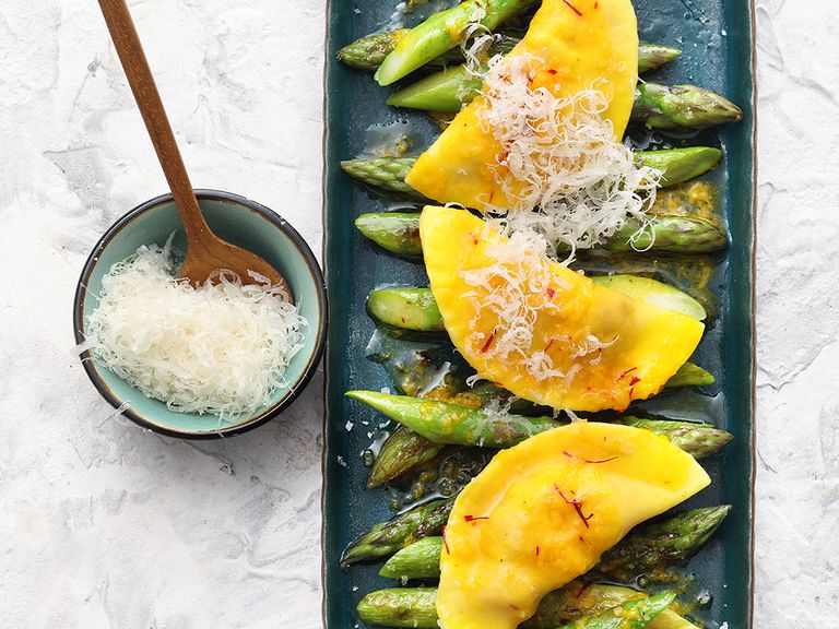 Der gegrillte grüne Spargel mit Lachs-Maultaschen und Safran-Knoblauch-Butter wird mit Parmesan verfeinert. Gegrillter grüner Spargel mit Lachs-Maultaschen und Safran-Knoblauch-Butter