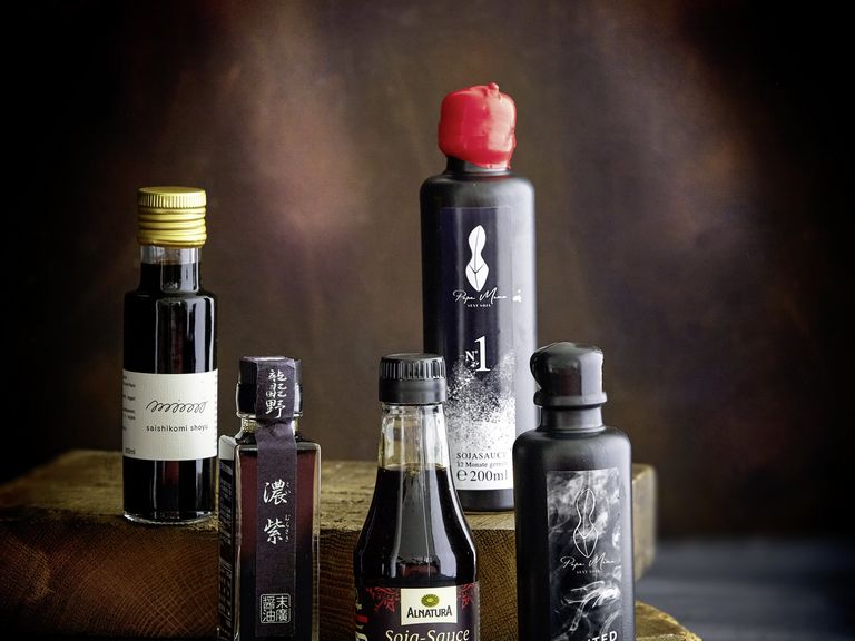 Die fünf besten Sojasaucen im Test überzeugen mit ihrer vielseitigen Würze. Beste Sojasauce Test, 5 Flaschen, dunkler Hintergrund