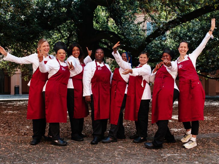 Teamfoto vom Restaurant Roots: Ausbilderin Nadia (Ukraine), Joy (Nigeria), Margarita (Kolumbien), Esther (Nigeria), Faithful (Nigeria), Nazma (Pakistan), Souschefin Fanta (Guinea) und Direktorin Jessica Rosval (v.l.n.r.). Modena-Roots-Restaurant-Team
